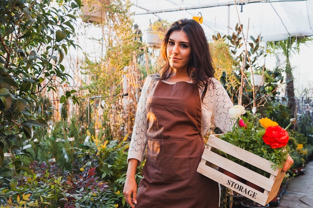 Encantadora mujer con flores en invernadero