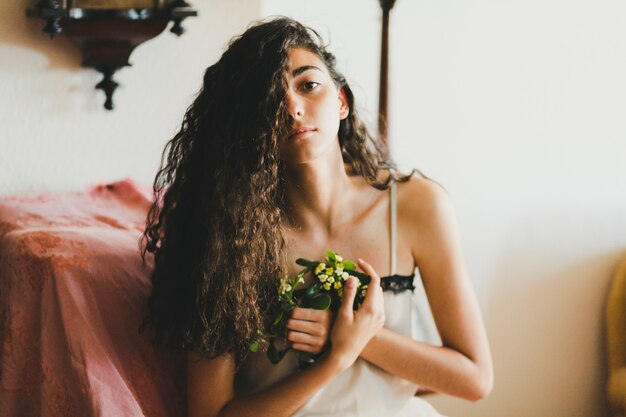 Encantadora mujer con flores mirando a cámara