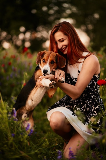 Encantadora mujer joven juega con un Beagle en un campo verde