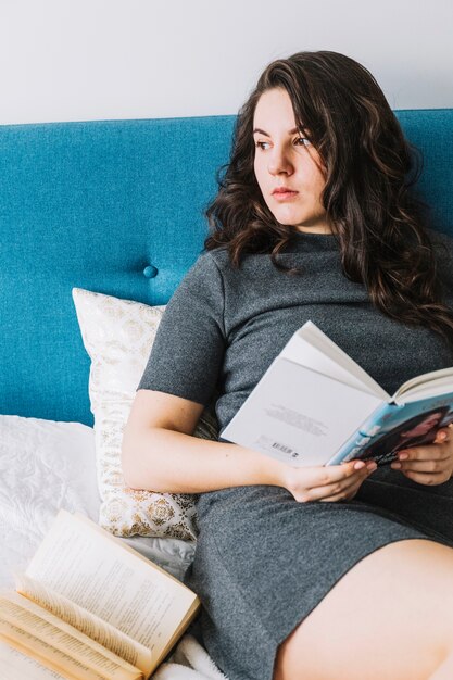 Encantadora mujer leyendo el libro en la cama