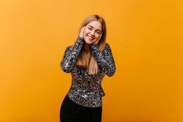 Encantadora mujer linda riendo en amarillo brillante. Retrato interior de mujer hermosa entusiasta lleva chaqueta brillante.