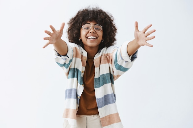 Foto gratuita encantadora mujer moderna afroamericana amable y linda en traje elegante tirando de las manos hacia para dar un abrazo