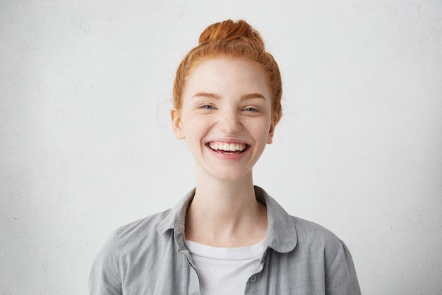 Encantadora mujer pelirroja con hermoso rostro pecoso vestido casualmente sonriendo