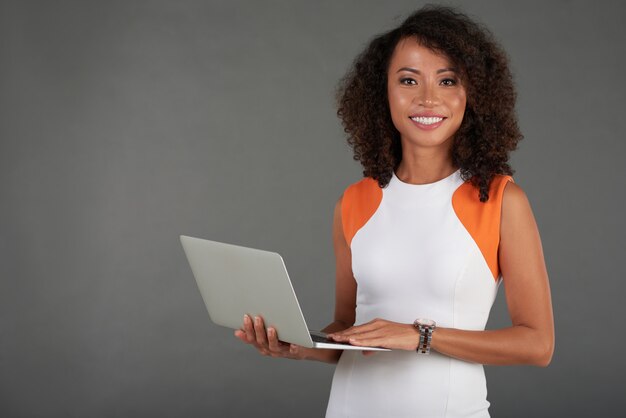 Encantadora mujer de pie con laptop y sonriendo