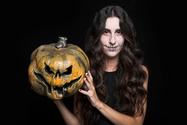 Encantadora mujer sosteniendo la calabaza de Halloween