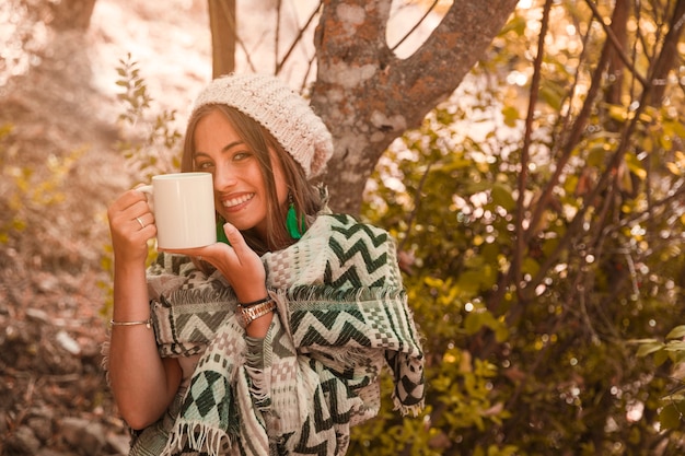 Encantadora mujer con taza en el bosque