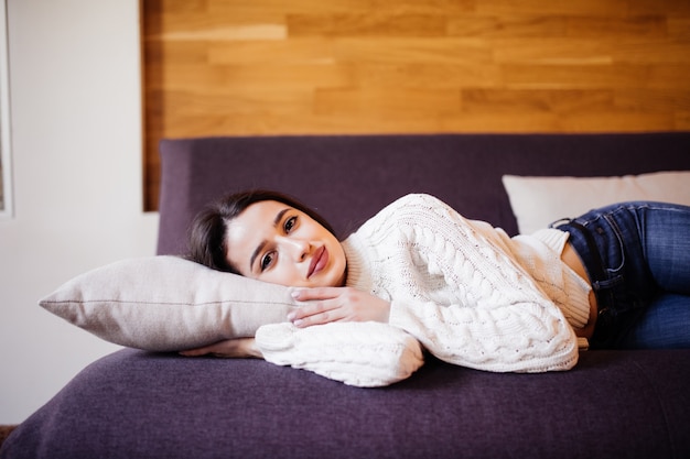 Encantadora mujer está tomando una siesta diaria entre el trabajo para hacer en el sofá oscuro en el apartamento de moda