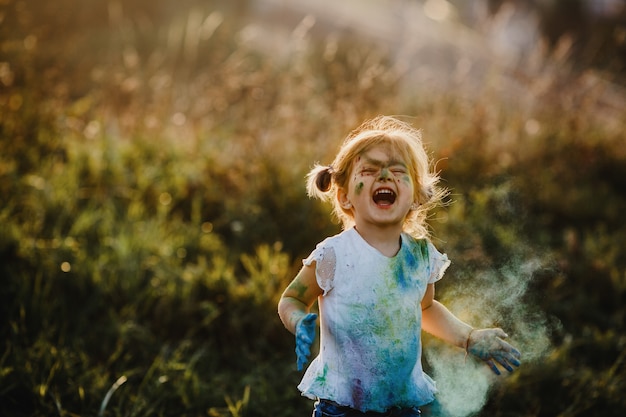 Encantadora niña con camisa blanca cubierta con diferentes pinturas