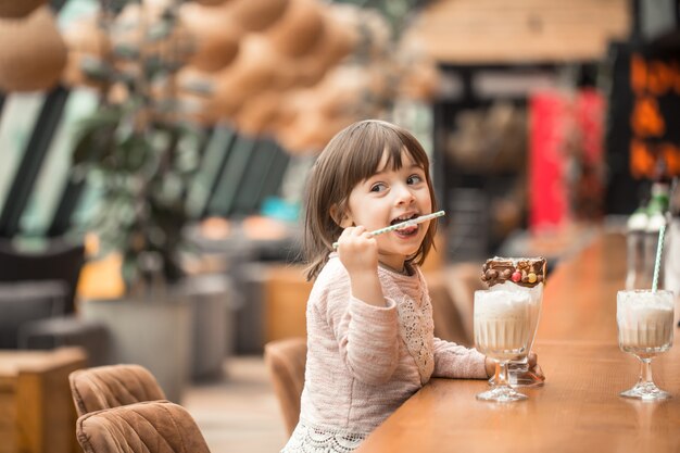 Encantadora niña divertida bebe un batido