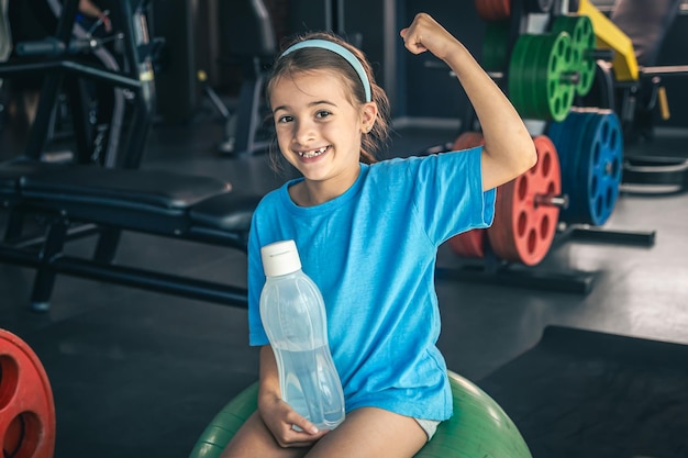 Foto gratuita la encantadora niña muestra sus bíceps trabajando en el gimnasio.