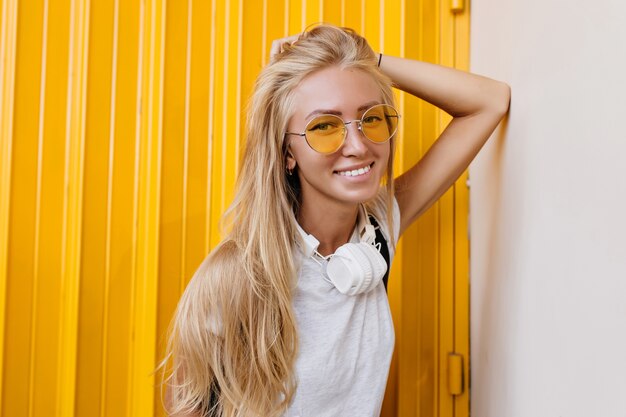 encantadora niña riendo de pelo largo con gafas de sol amarillas.