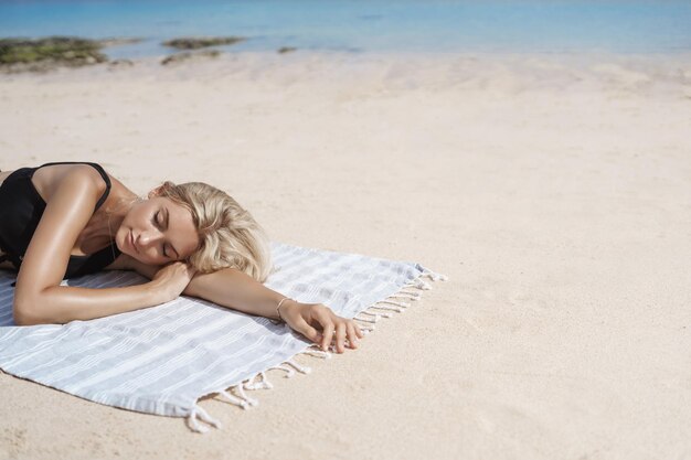 Encantadora novia relajada y despreocupada tomando una siesta durante la mentira para tomar el sol manta de playa de arena ojos cerrados sonrisa feliz cerca de la orilla del océano disfrutar de vacaciones de verano viajando paraíso tropical resort