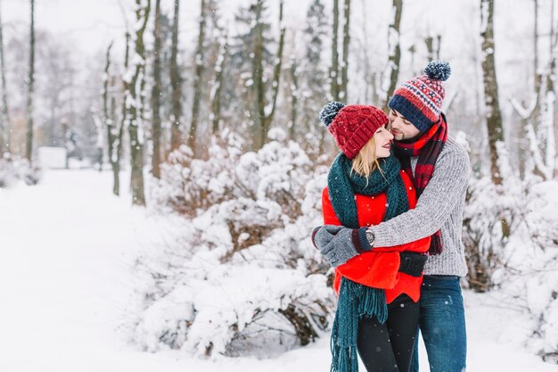 Encantadora pareja abrazándose en el bosque nevado