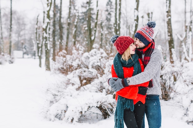 Encantadora pareja abrazándose en el bosque nevado