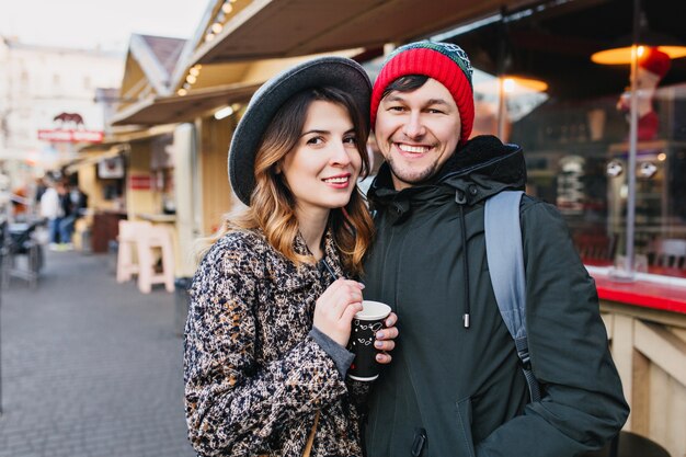 Encantadora pareja alegre escalofriante, abrazándose en la calle en Navidad. Verdaderas emociones de amor, divertirse, disfrutar de la unión, las citas, la relación romántica, la felicidad juntos.