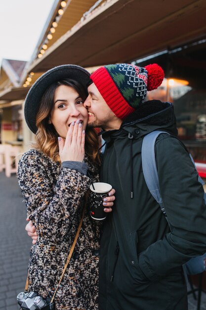 Encantadora pareja alegre escalofriante, abrazándose en la calle en Navidad. Verdaderas emociones de amor, divertirse, disfrutar de la unión, las citas, la relación romántica, la felicidad juntos.