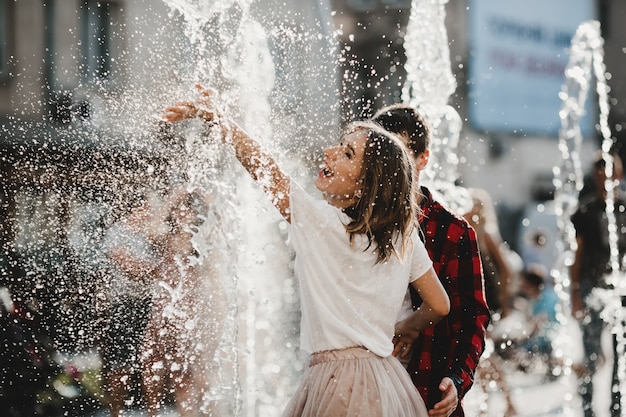 Foto gratuita la encantadora pareja enamorada jugando con una fuente