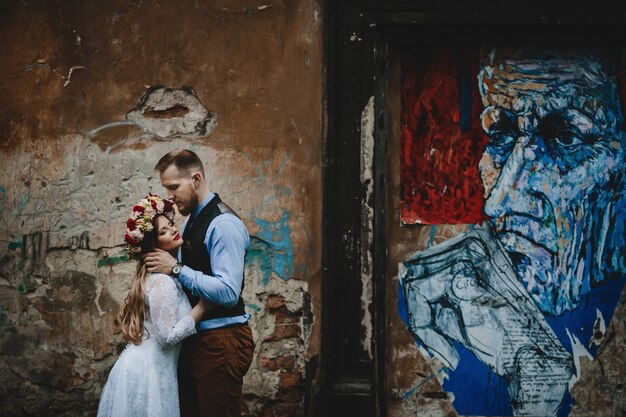 La encantadora pareja de enamorados abrazándose cerca de la pared