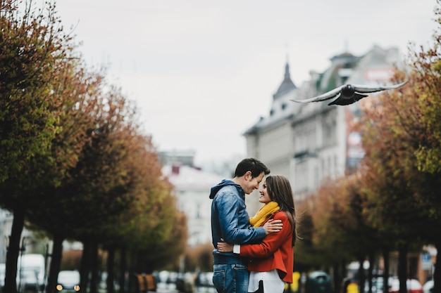 La encantadora pareja de enamorados abrazándose y de pie en el callejón