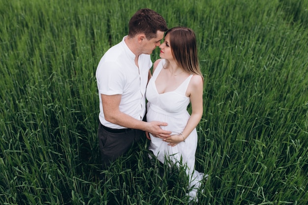 La encantadora pareja de enamorados abrazándose y de pie en el campo