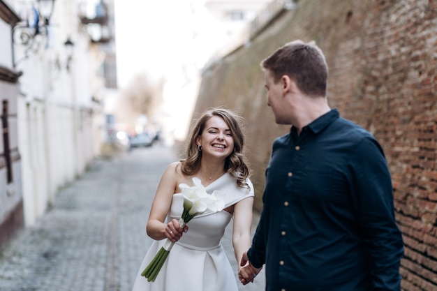 La encantadora pareja de enamorados caminando por la calle estrecha