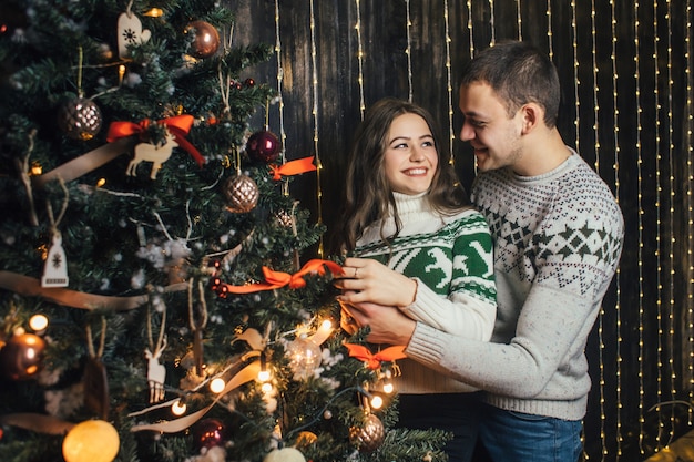 La encantadora pareja de enamorados decora un árbol de Navidad