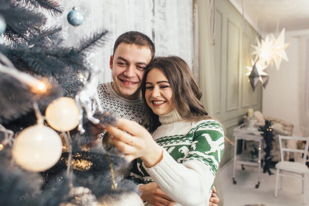 La encantadora pareja de enamorados decora un árbol de Navidad