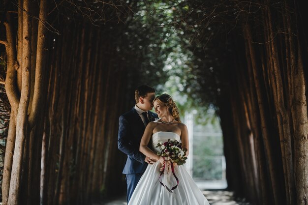 La encantadora pareja de enamorados de pie en el bosque