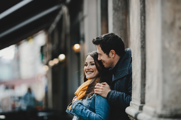 La encantadora pareja de enamorados de pie cerca del edificio