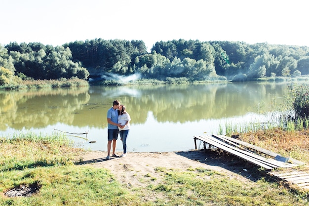 Encantadora pareja espera abrazando junto al río verde