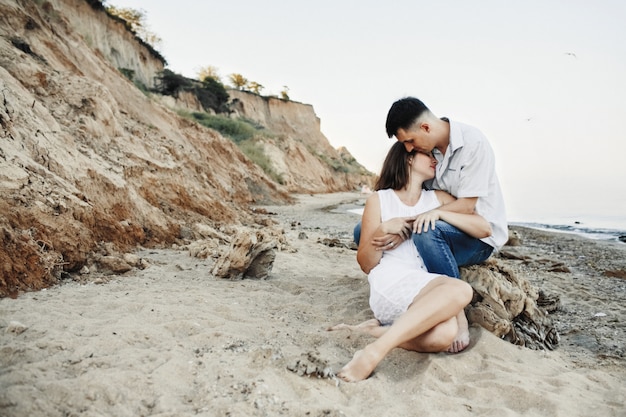 Encantadora pareja está sentada y apoyada en la hermosa playa