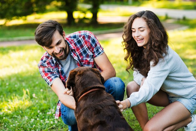 Encantadora pareja joven jugando con su perro en el jardín