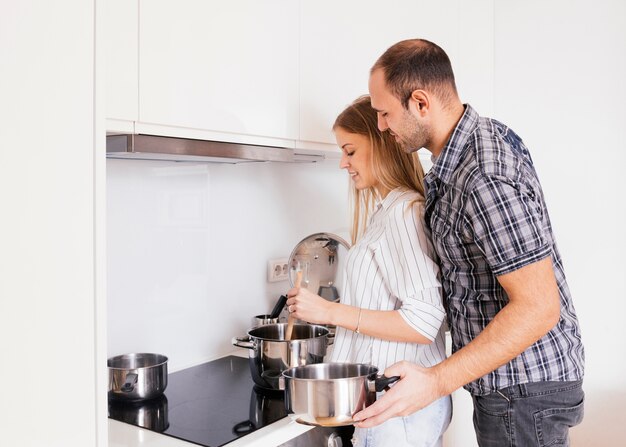 Encantadora pareja joven preparando la comida en la cocina moderna