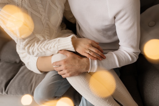 Encantadora pareja joven en ropa de hogar blanca acogedora posa en una habitación con árbol de Navidad