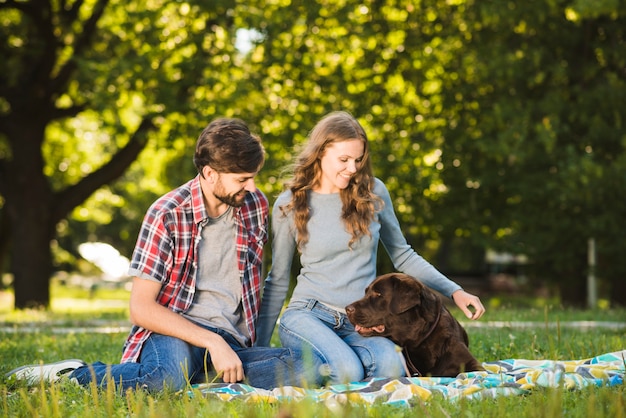 Encantadora pareja joven sentada con su perro en el jardín