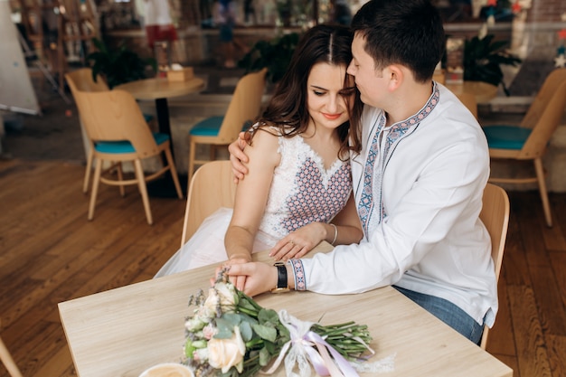 Encantadora pareja joven se sienta en una mesa en un acogedor café