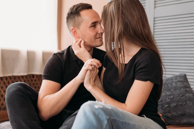 Encantadora pareja joven vestida en estilo casual se sienta en el piso