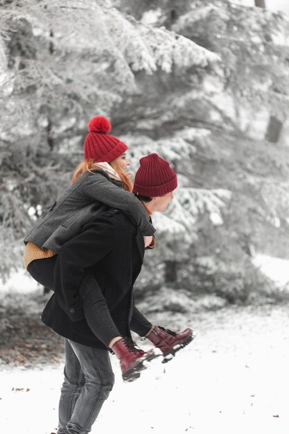 Encantadora pareja jugando en la nieve de lado