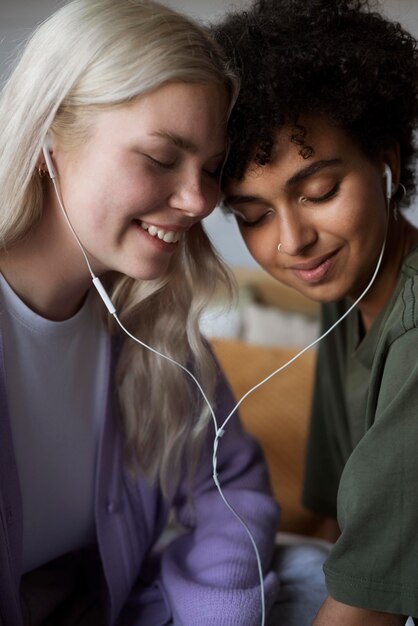 Encantadora pareja de lesbianas escuchando música con auriculares