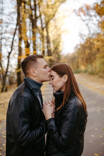 Encantadora pareja posando en el bosque de otoño, amantes caminando en el parque