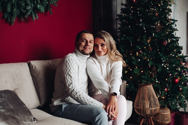 Encantadora pareja posando para una foto de vacaciones cerca del árbol de Navidad