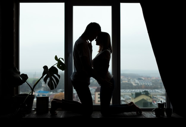Encantadora pareja posando junto a la ventana