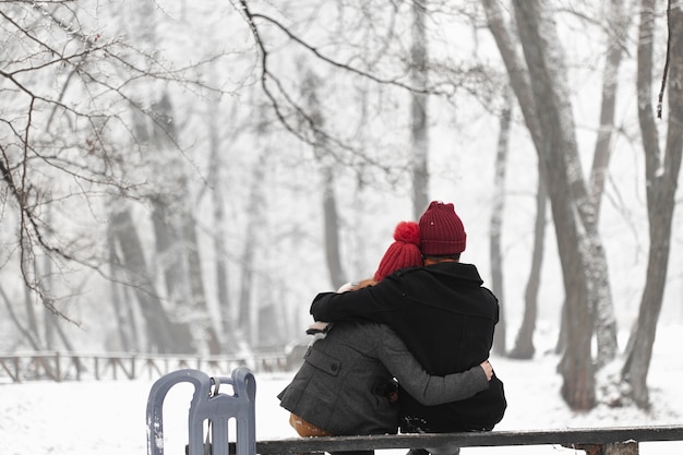 Foto gratuita encantadora pareja sentada en un banco y abrazando