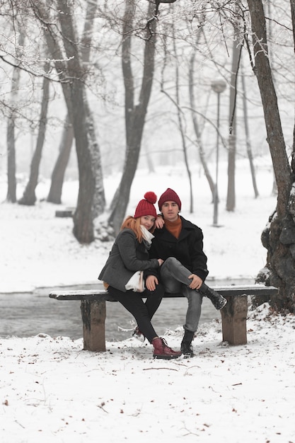 Encantadora pareja sentada en un banco vista larga