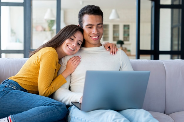 Encantadora pareja usando una laptop en el sofá