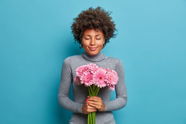 Encantadora romántica mujer afroamericana sostiene un hermoso ramo de flores de gerbera