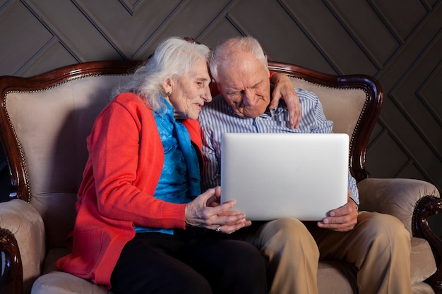 Foto gratuita encantadora senior hombre y mujer sosteniendo una laptop