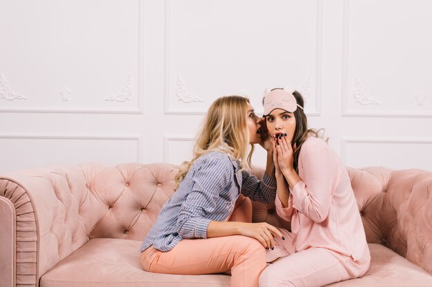 Encantadoras mujeres chismeando en el sofá