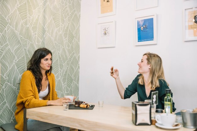 Encantadoras mujeres tomando fotos en la cafetería