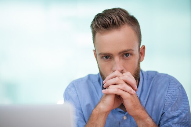 Encargado serio sentado perturbados en la computadora portátil